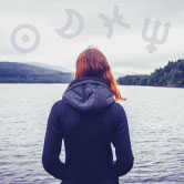 woman looking over water with astrology symbols around