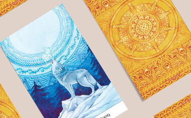 Tarot cards are spread out on a table, including one that shows a wolf howling at the night sky.