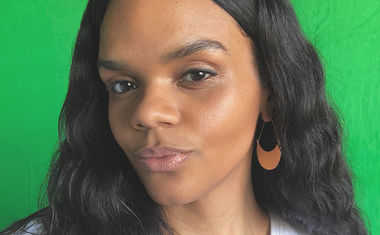 A photograph of astrologer Taylor Moon, a Black woman with dark hair and gold earrings.
