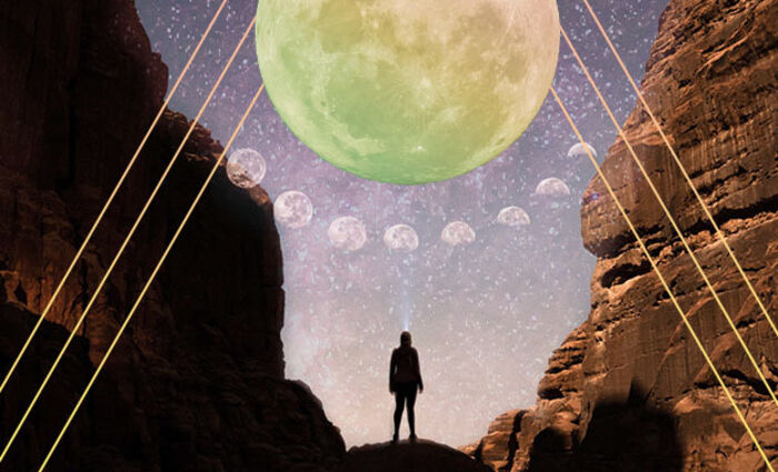 A silhouette stands in a canyon and looks up at an enormous full moon in the sky.