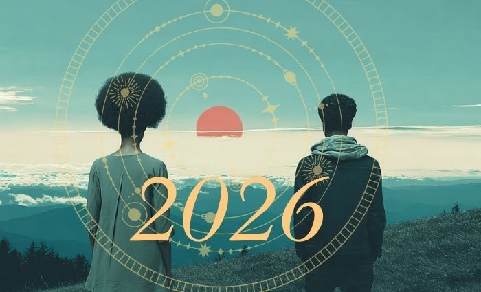 Two people stand on a mountaintop, looking toward a red sun and the horizon of 2026 astrology.