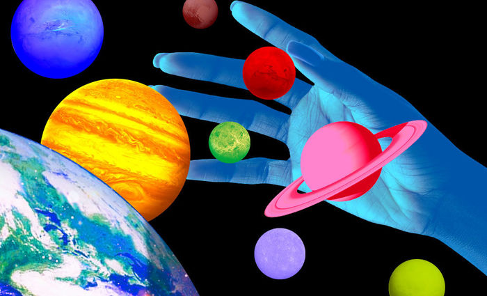 Technicolor planets float against a black background as a blue hand reaches out to grab them.