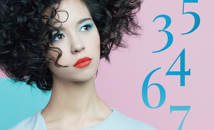 A woman with short curly hair looks at numbers for the Numerology Personal Month in October 2022.