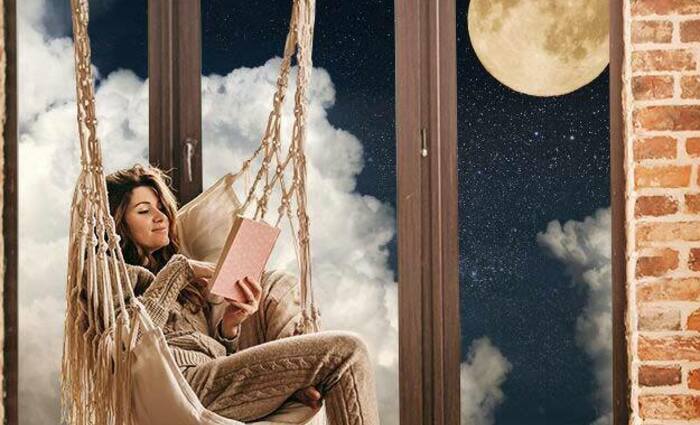 A woman relieves stress by sitting in a hammock and reading a book.