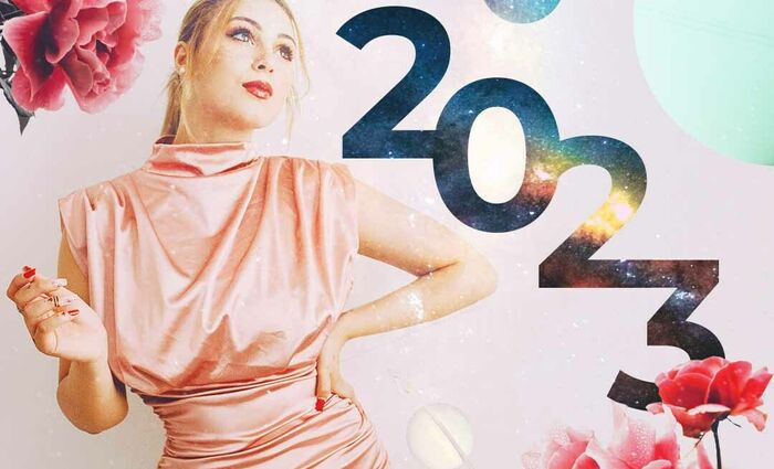 A woman in a pink dress stands against a rosy background for the 2023 general horoscope.