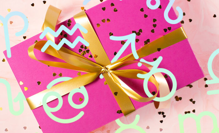A pink gift box with a gold ribbon is surrounded by zodiac sign symbols.
