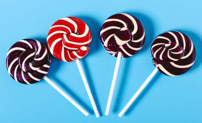 Four giant lollipops against a blue background represent the candy that each zodiac sign enjoys.