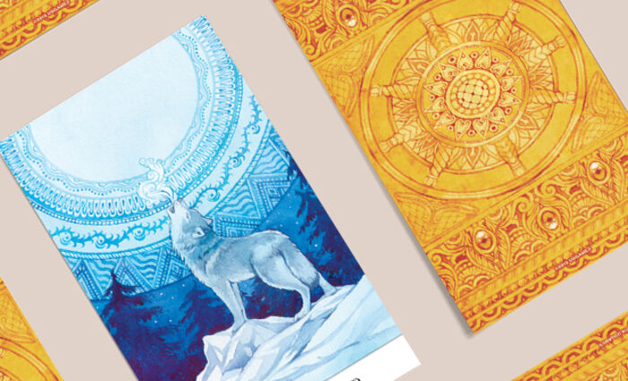 Tarot cards are spread out on a table, including one that shows a wolf howling at the night sky.