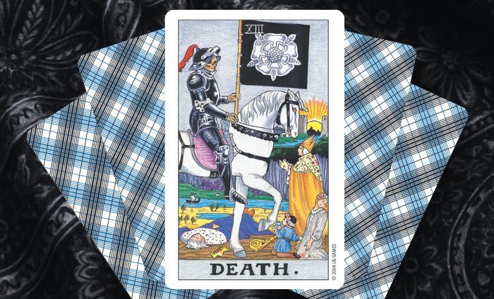 A classic Death card rests on a floral tapestry.