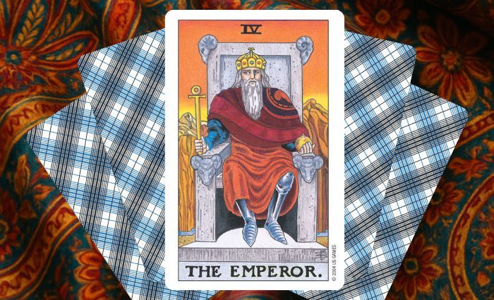 A classic Emperor card rests on a floral tapestry.