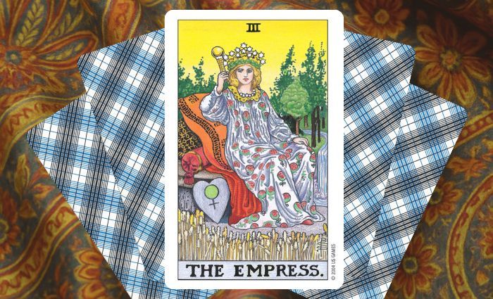 A classic Empress card rests on a floral tapestry.