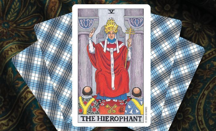 A classic Hierophant card rests on a floral tapestry.