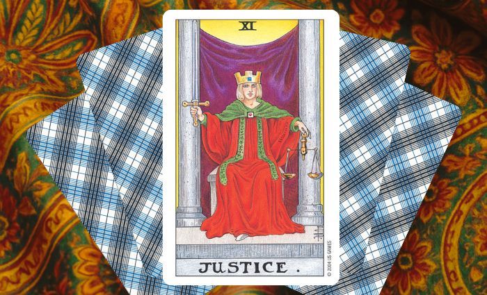 A classic Justice card rests on a floral tapestry.