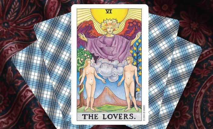 A classic Lovers card rests on a floral tapestry.