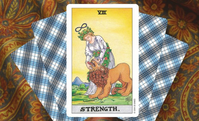A classic Strength card rests on a floral tapestry.