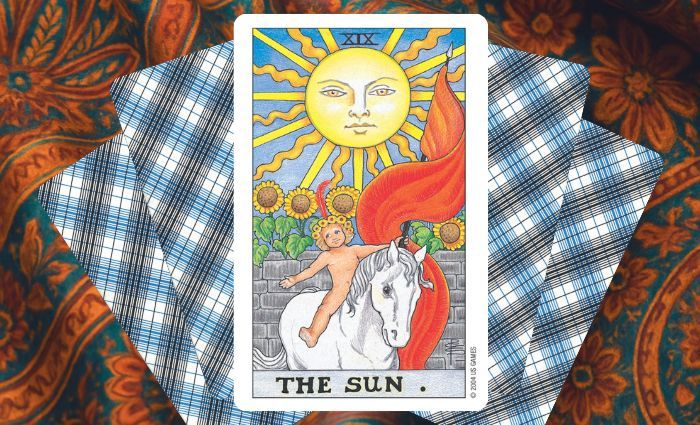 A classic Sun card rests on a floral tapestry.