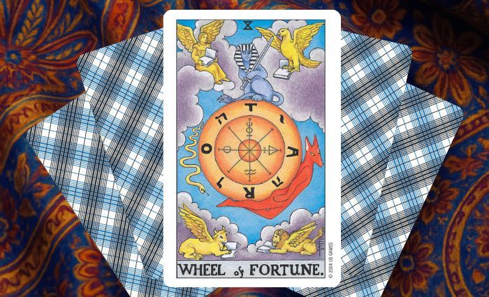 A classic Wheel of Fortune card rests on a floral tapestry.